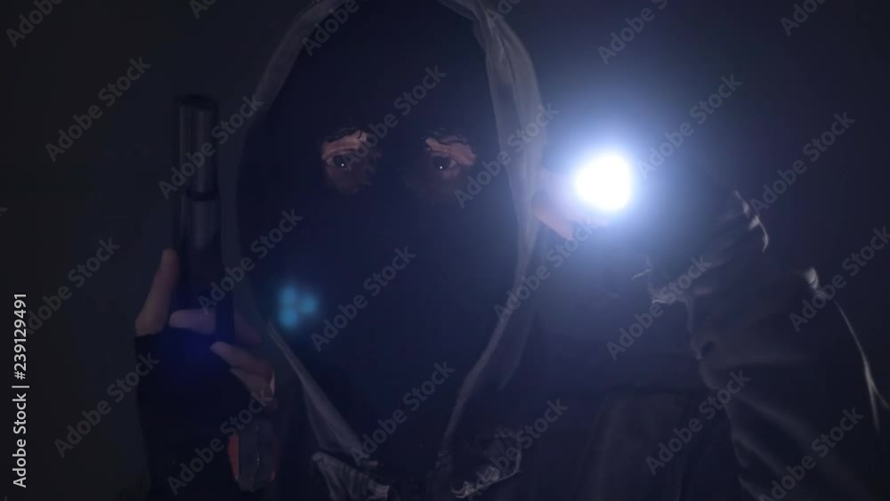 Armed burglar intruder with flashlight torch at night, low key selective focus, slow motion Armed burglar intruder with flashlight torch at night, low key selective focus, slow motion