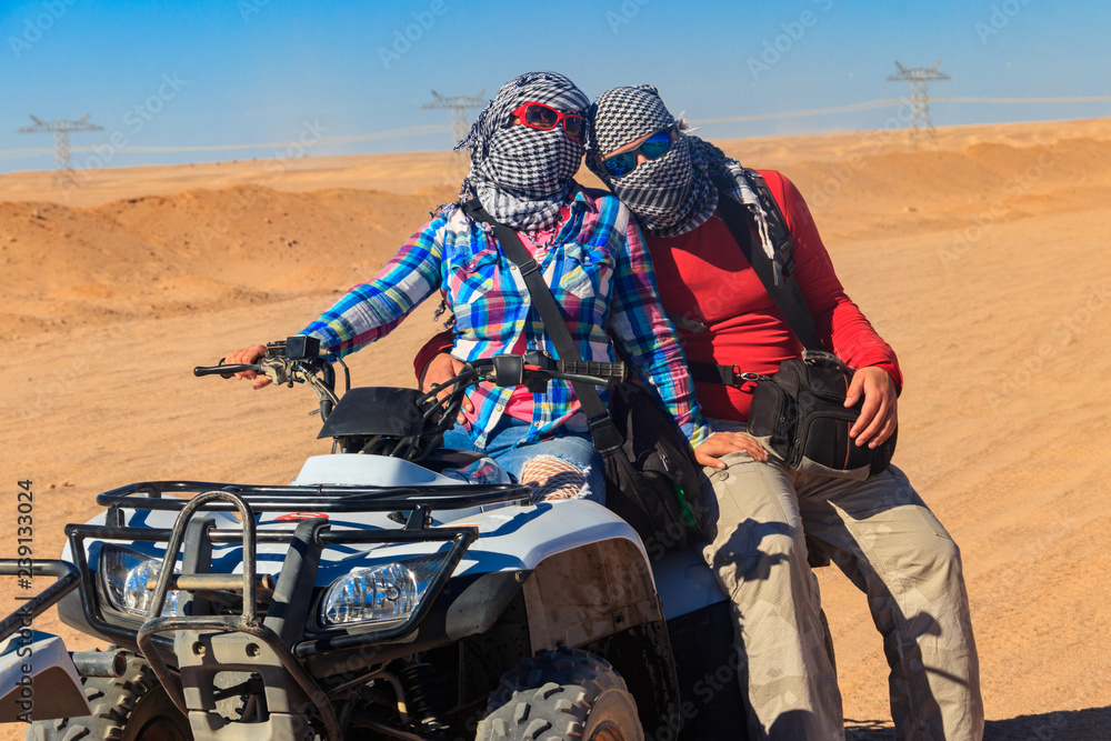 Obraz premium Young couple in safari trip through egyptian desert driving ATV. Quad bikes safari in the desert near Hurghada, Egypt