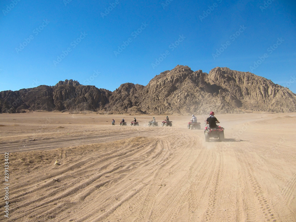 Caravan ATV racing at high speed through the desert raising dust