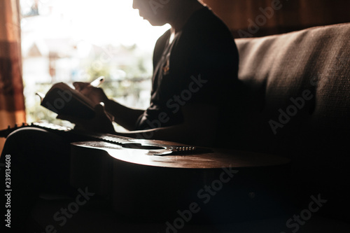 guitar and man write on book sitdown on sofa photo