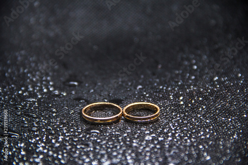 two wedding rings on a black background with water