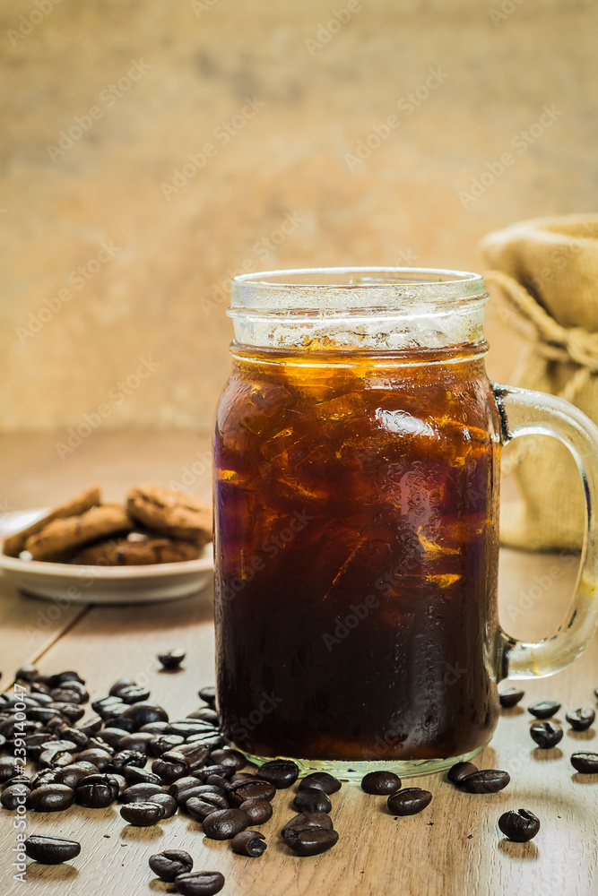 Iced black coffee with coffee beans on wood table Iced black coffee with coffee beans on wood table