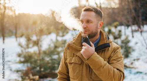 Modern young man with a beard fun smoking Electronic Cigarette