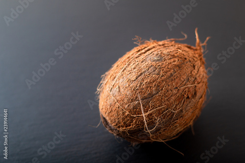 Whole single organic Tropical coconut fruit on black slate stone background with copy space
