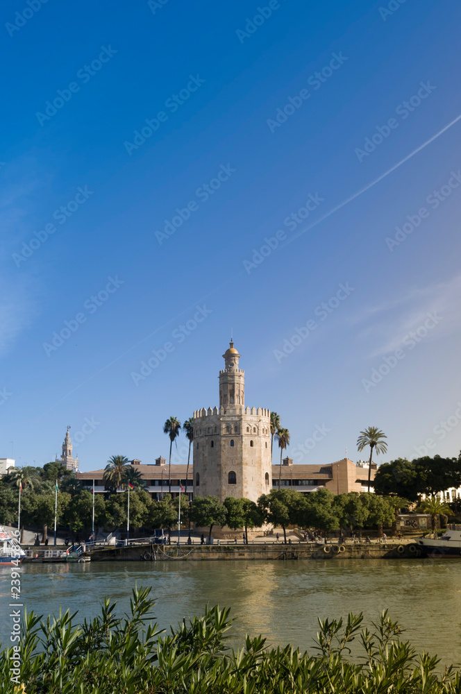 Golden Tower in Seville with the Guadalquivir river and a beautiful blue sky at sunset (Torre del Oro, Sevilla) Andalusia, Spain