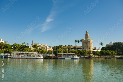 Golden Tower in Seville with the Guadalquivir river and a beautiful blue sky at sunset (Torre del Oro, Sevilla) Andalusia, Spain