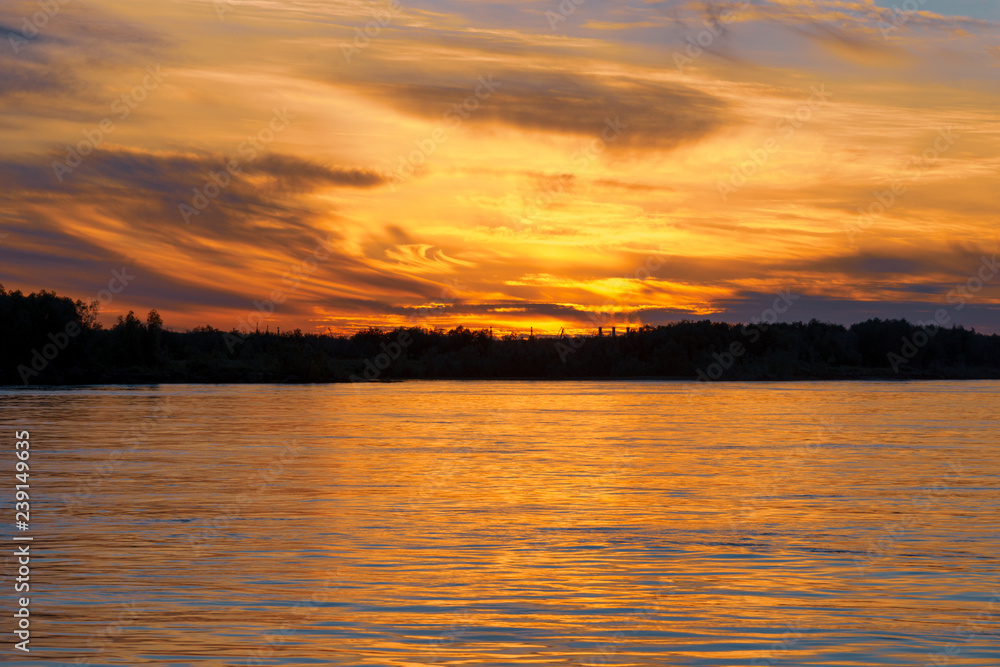 Obraz premium Beautiful sunset on the river. Summer sunset or sunrise landscape with golden light in Yakutia, Republic of Sakha, Russia. Riverscape taken from a ferry on river Lena