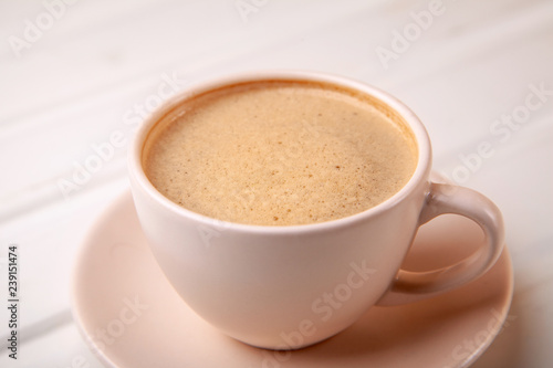 Cup of coffee with foam on white table