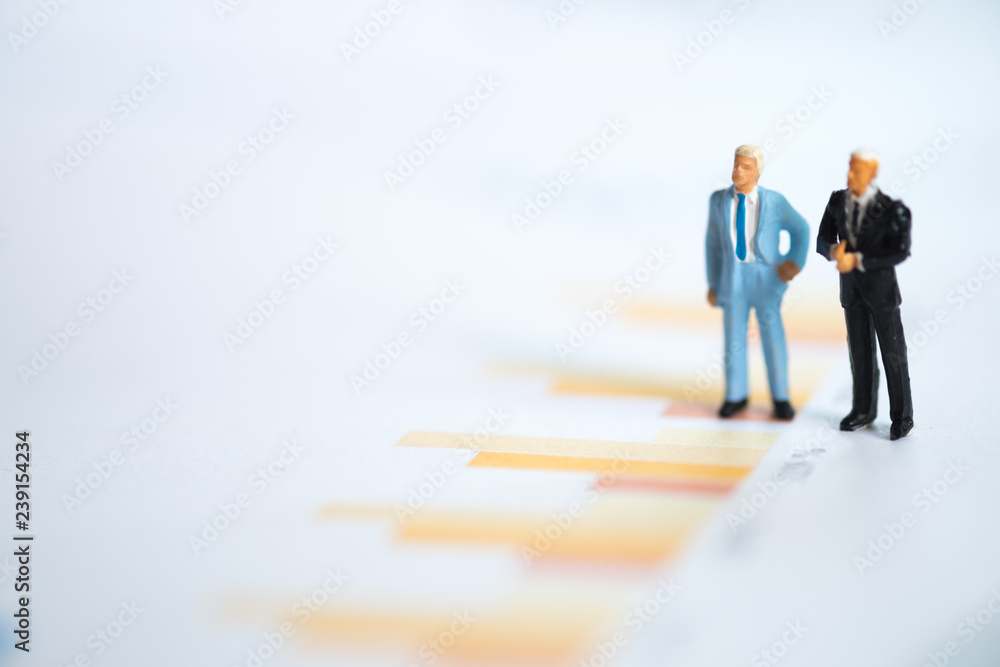 Miniature people: Businessman thinking with project for investment Miniature people: Businessman thinking with project for investment