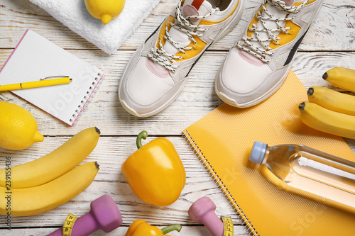 Flat lay composition with sport items, healthy food and notebooks on wooden background. Weight loss concept