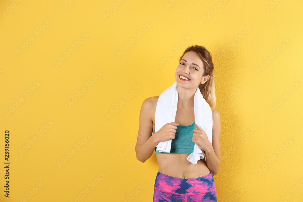 Beautiful young woman in sportswear with towel on color background. Space for text Beautiful young woman in sportswear with towel on color background. Space for text