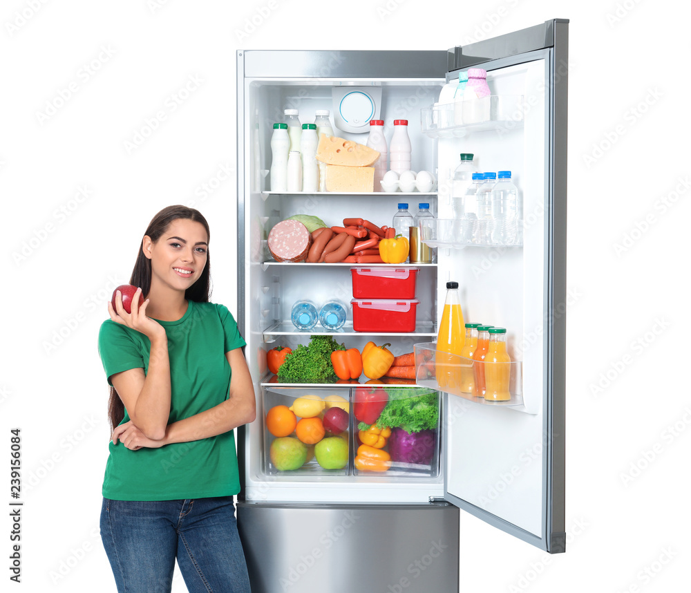 Young woman with apple near open refrigerator on white background Young woman with apple near open refrigerator on white background