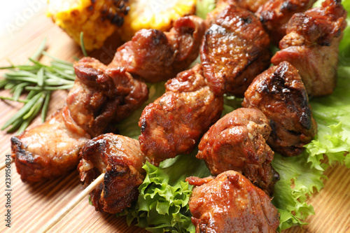 Barbecued meat with garnish on wooden background, closeup