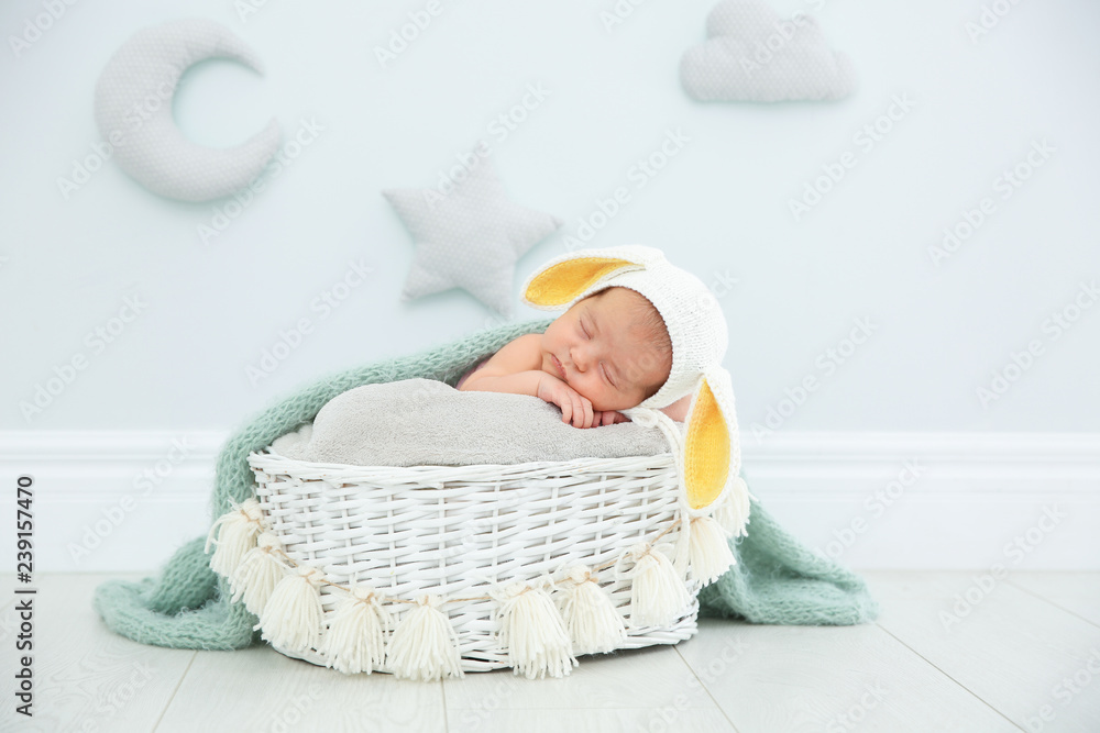 Fototapeta premium Adorable newborn child wearing bunny ears hat in baby nest indoors