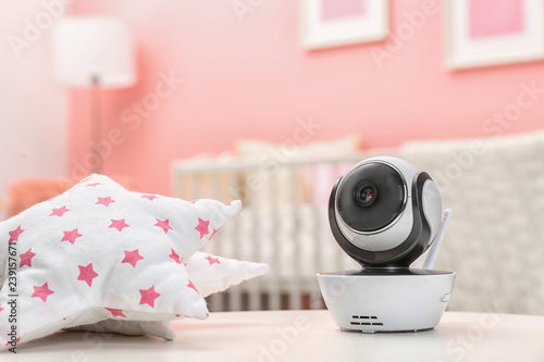 Baby monitor and toy on table in room, space for text. CCTV equipment