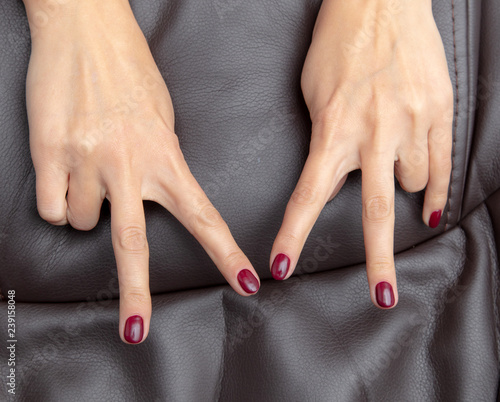 Girl s hand with a red manicure on a brown background