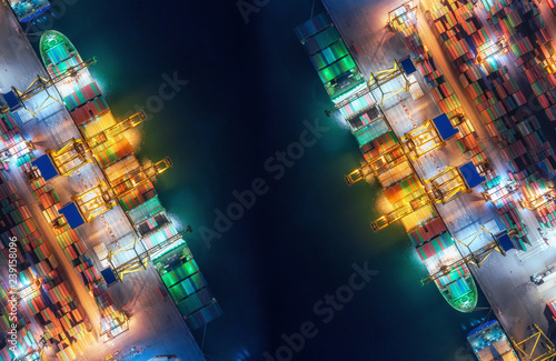 Aerial top view container ship at sea port and working crane bridge loading container for import export, shipping or transportation concept background.