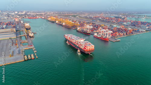 Aerial view Tug boats drag container ship to sea port and working crane bridge loading container for import  export or transportation concept background. © Pawinee