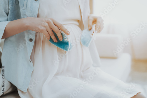 Close up. Pregnant Woman Holds Shoes for Newborn.