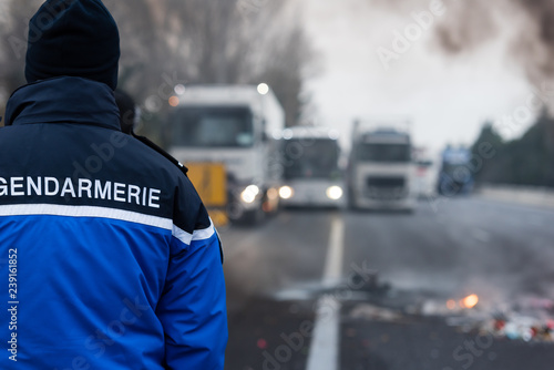 Gendarme de dos face à des camions bloqué sur l'autoroute - Manifestation