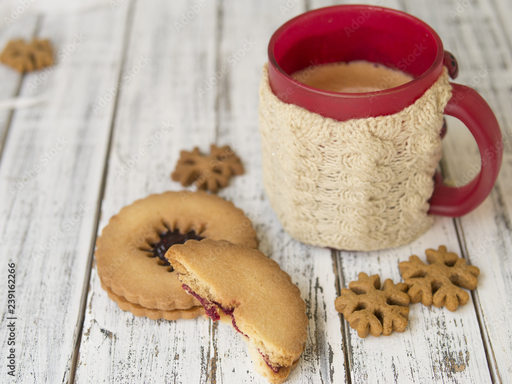 Winter morning, cup of coffee with knitted cup holders, gingerbread and vanilla cookies on a white wooden background.Cozy winter breakfast.Ideal for winter couple in love. Copy space, selective focus Winter morning, cup of coffee with knitted cup holders, gingerbread and vanilla cookies on a white wooden background.Cozy winter breakfast.Ideal for winter couple in love. Copy space, selective focus
