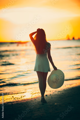 Beautiful young girl on the beach with hat at sunset photo