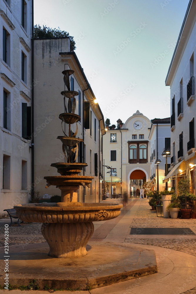 Fototapeta premium treviso di sera per la città e strada con fontana in italia, europa, evening in treviso city in the street with fountain in italy, europe