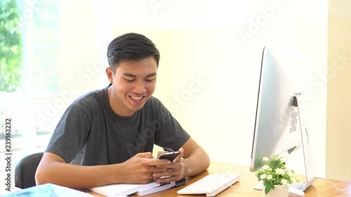 Student learning online study concept: Asian Young man sitting holding smartphone chatting in home for e-learning in educational technology by self photo