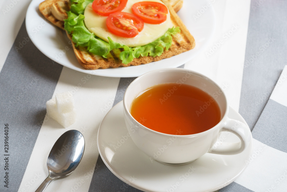 Fresh, tasty breakfast with a sandwich and tea on a light background. Fresh, tasty breakfast with a sandwich and tea on a light background.