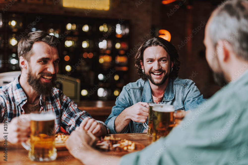 Cheerful friends chatting and enjoying drinks at pub Cheerful friends chatting and enjoying drinks at pub