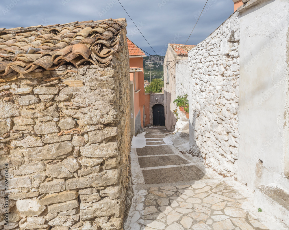 Old narrow street with traditional stone houses in Village Krini, corfu, greece