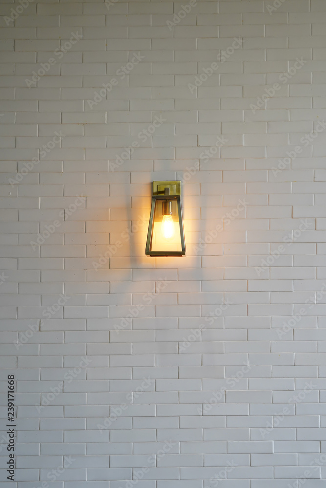 Square steel lamp tungsten/warm light on the white brick wall. Square steel lamp tungsten/warm light on the white brick wall.