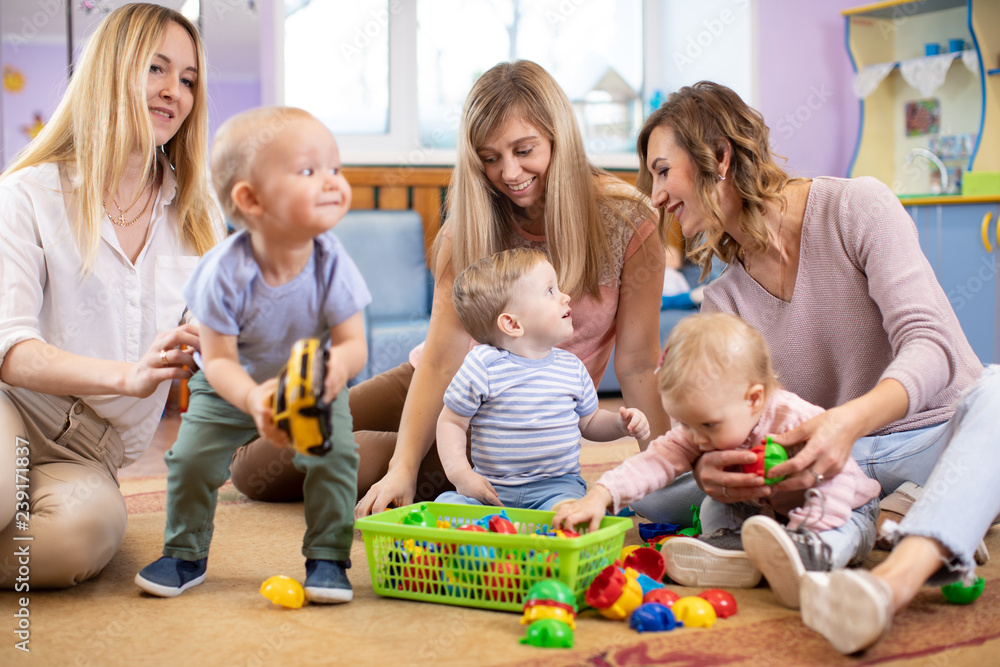 Three woman friends with toddlers playing on the floor in sitting room Three woman friends with toddlers playing on the floor in sitting room
