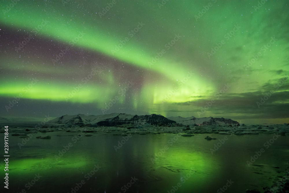 Northern Lights over frozen glacier lake and mountains in Iceland winter
