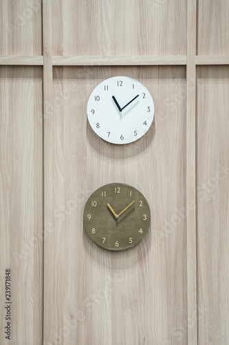 two difference clocks hang on to wooden background.