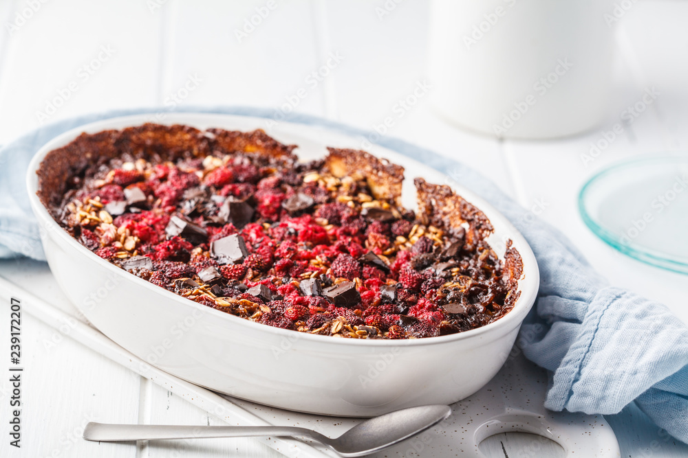 Baked oatmeal with berries and chocolate in a white dish. Baked oatmeal with berries and chocolate in a white dish.