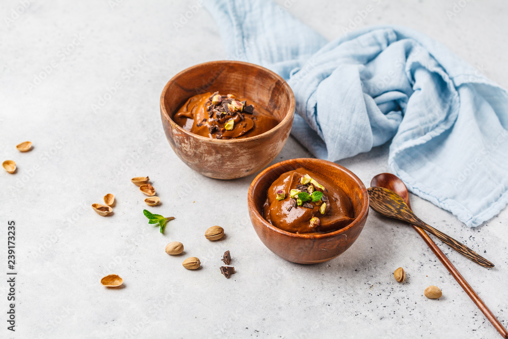 Fototapeta premium Avocado chocolate mousse with pistachios in wooden bowl on white background.