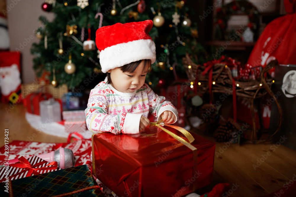 toddler baby girl wearing santa claus costume open gift box in front of christmas tree toddler baby girl wearing santa claus costume open gift box in front of christmas tree
