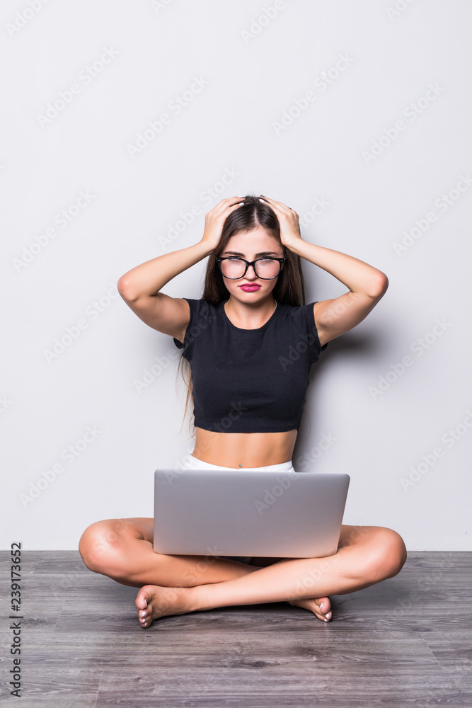 Beautiful young woman sitting on the floor working using laptop at home stressed with hand on head, shocked with shame and surprise face, angry and frustrated. Fear and upset for mistake. Beautiful young woman sitting on the floor working using laptop at home stressed with hand on head, shocked with shame and surprise face, angry and frustrated. Fear and upset for mistake.