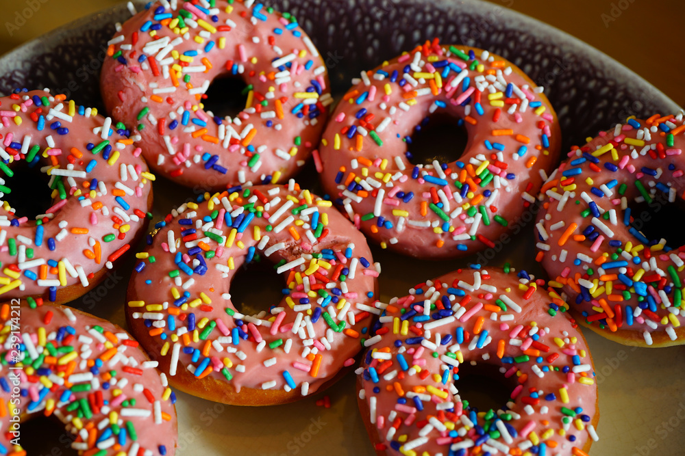 Fresh donuts with pink icing and colorful sprinkles