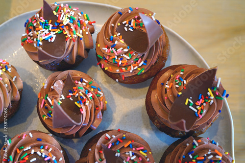Platter of chocolate cupcakes with buttercream frosting and colorful sprinkles