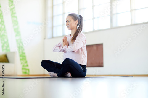 Young active sportswoman sitting on the floor of gy or yoga studio and exercising alone Free Download Young active sportswoman sitting on the floor of gy or yoga studio and exercising alone - GFXLoad
