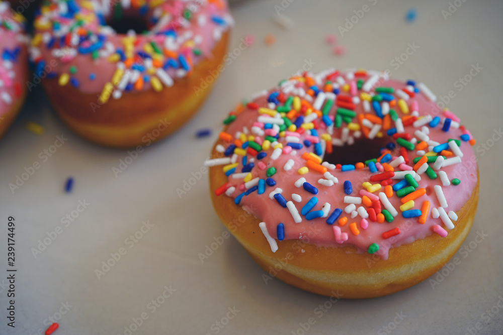 Fresh donuts with pink icing and colorful sprinkles