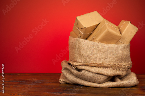 Christmas presents wrapped in ecological paper in a gift sack on a wooden table