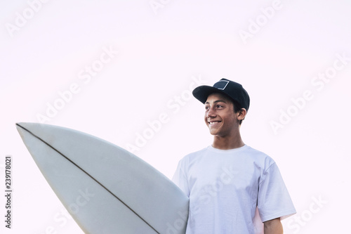 Canvas Print Nice portrait of young teenager with white surf board and t-shirt smiling and lo