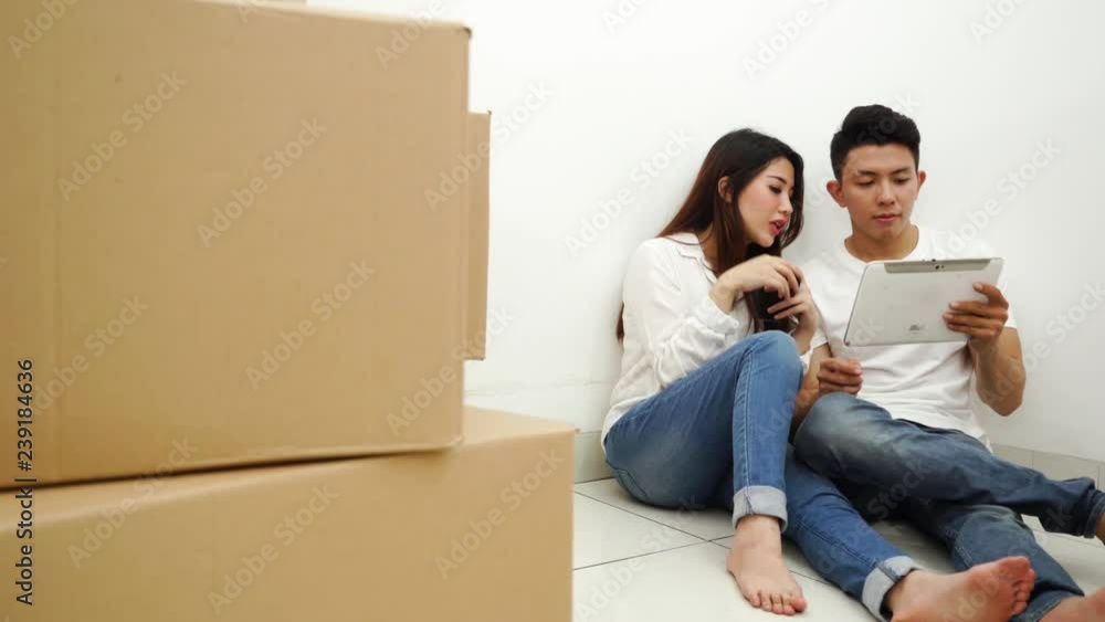 Happy young couple discussing in new house while sitting on the floor and using a digital tablet. Shot in 4k resolution Happy young couple discussing in new house while sitting on the floor and using a digital tablet. Shot in 4k resolution