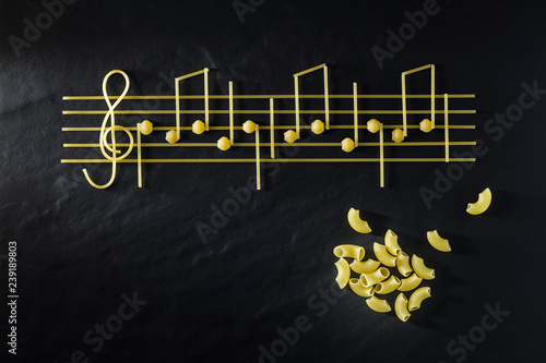 Musical Italian pasta in the form of notes, isolated on a black textural background.