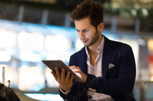 Young manager using a digital tablet outdoor in a modern city at night photo