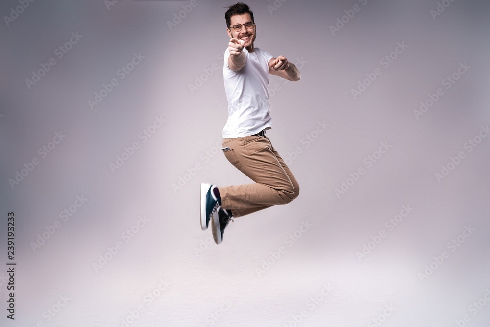 handsome man casual dressed celebrating and jumping on gray background