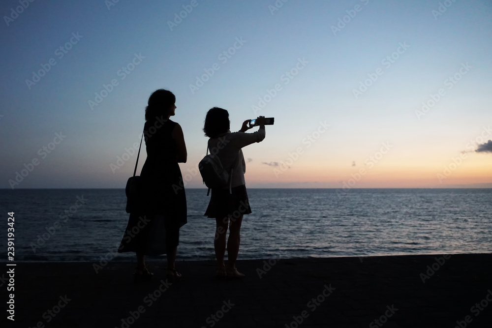 Girls take pictures of the sunset on the phone.Copy space.